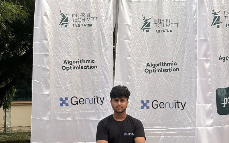 Karthikeya in front of the Genuity sponsor wall at Inter-IIT Tech Meet 14.0